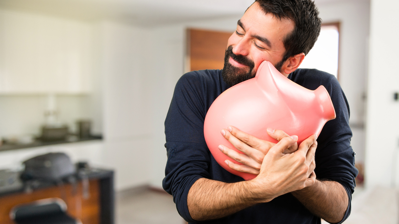 Мужчина обнимает розовую свинью копилку 