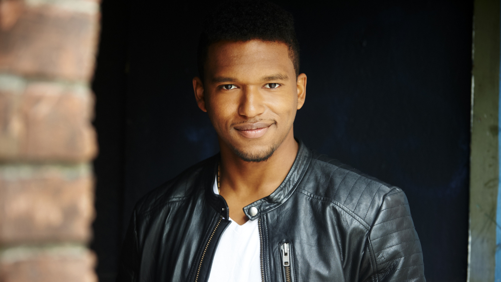 Красивый мужчина в черной куртке, актер Ловелл Адамс-Грей