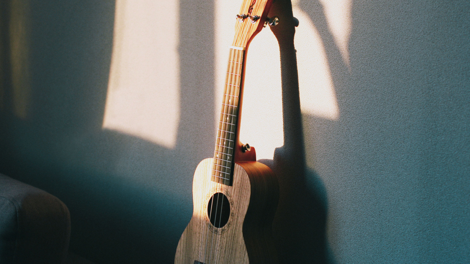 Желтая гитара стоит у серой стены