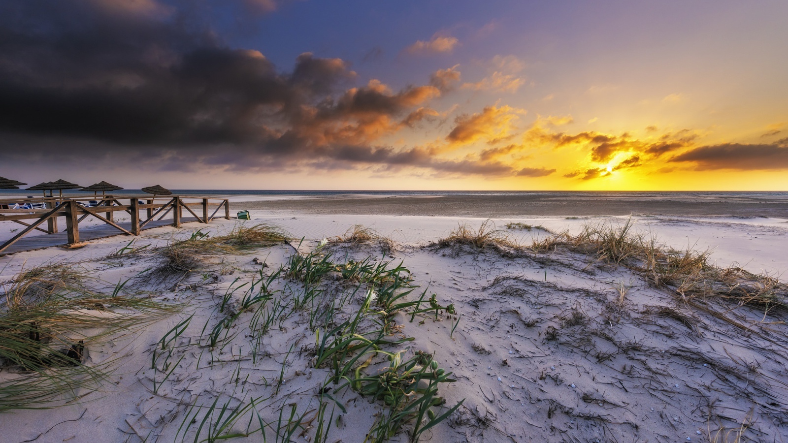 Белый песок в траве на берегу под красивым небом на закате