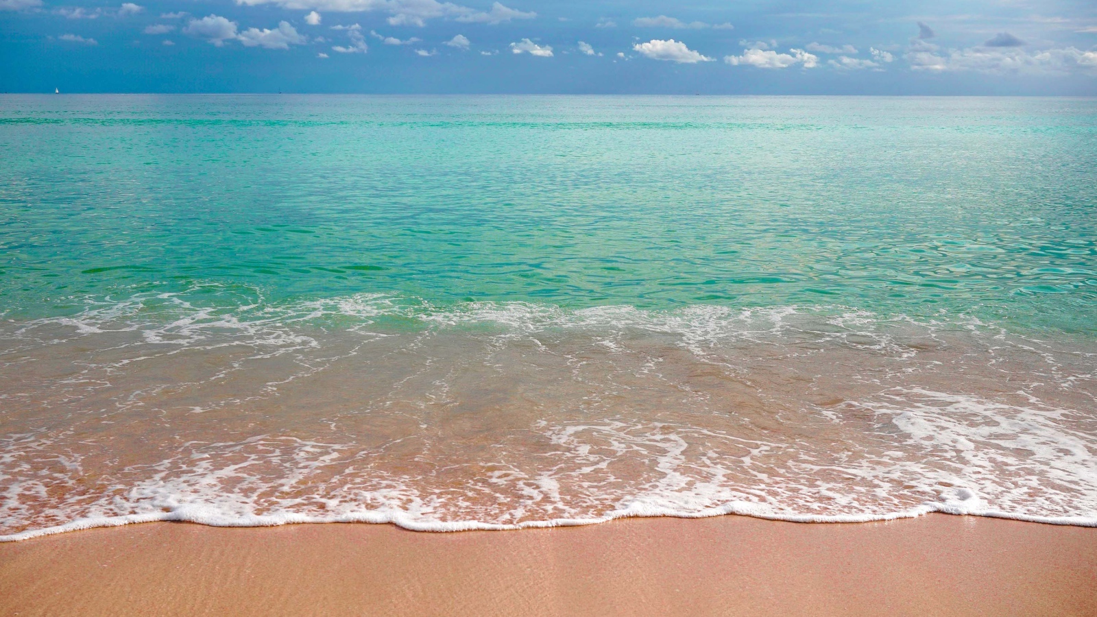 Волны голубого океана на желтом песке под голубым небом