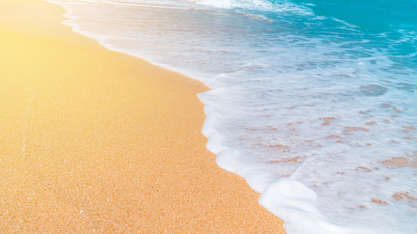 Белые волны океана омывают желтый горячий песок на пляже