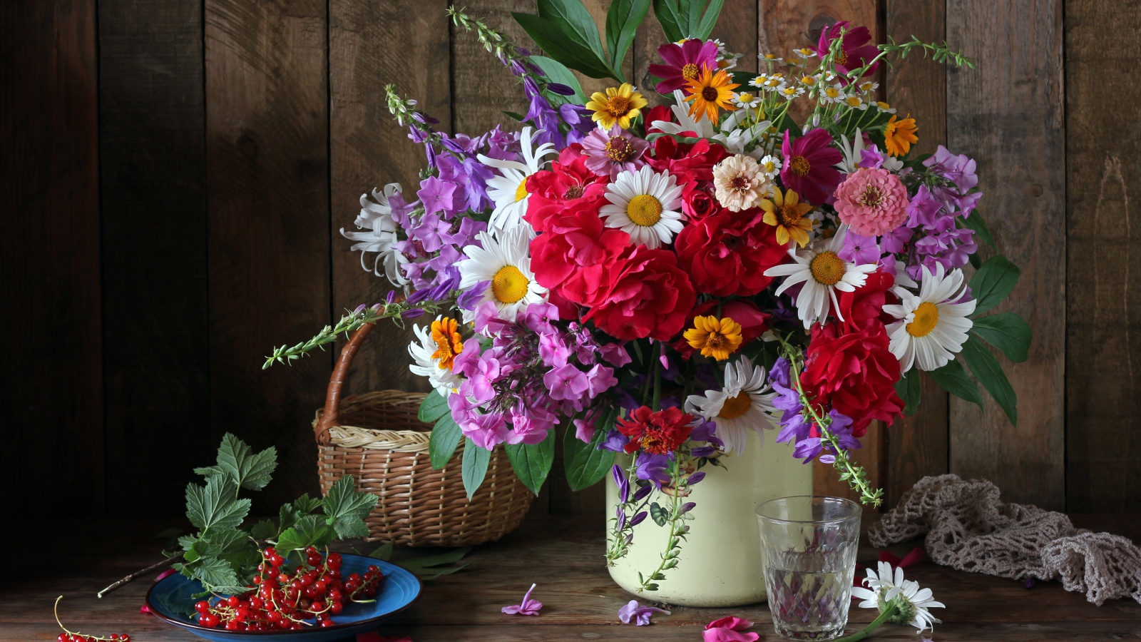 Красивый букет стоит на  столе с красной смородиной