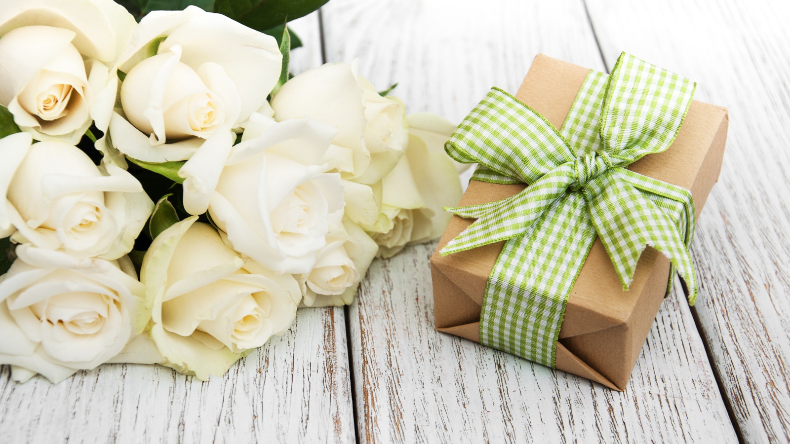 Букет белых роз на столе с подарком
