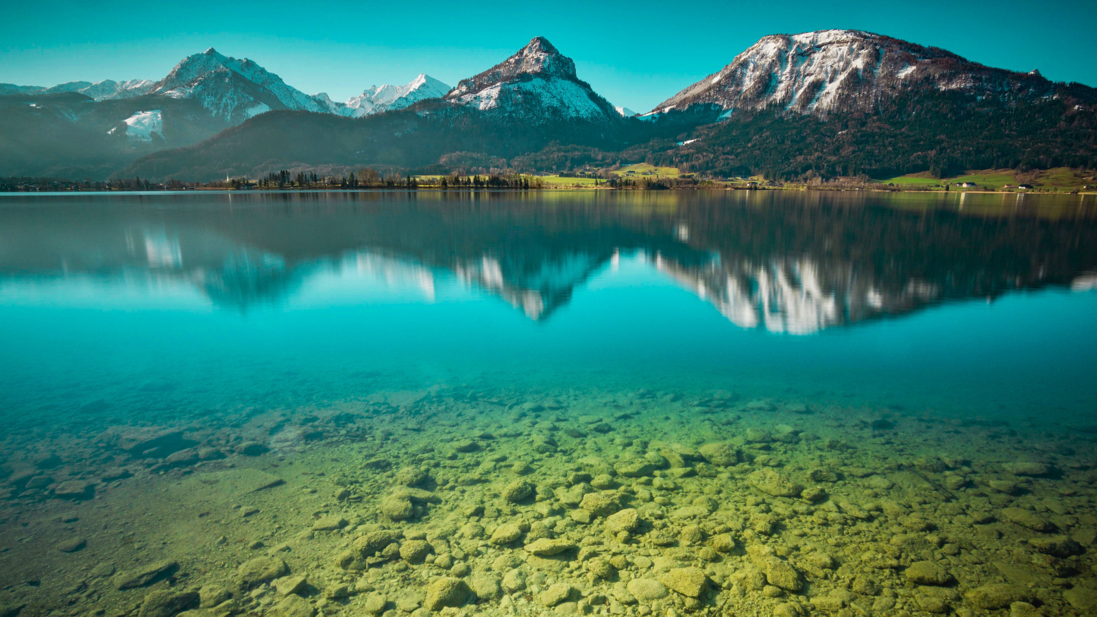Заснеженные горы отражаются в чистой воде озера 
