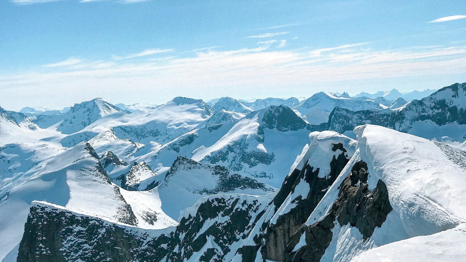 Верхушки заснеженных гор в лучах солнца под голубым небом 