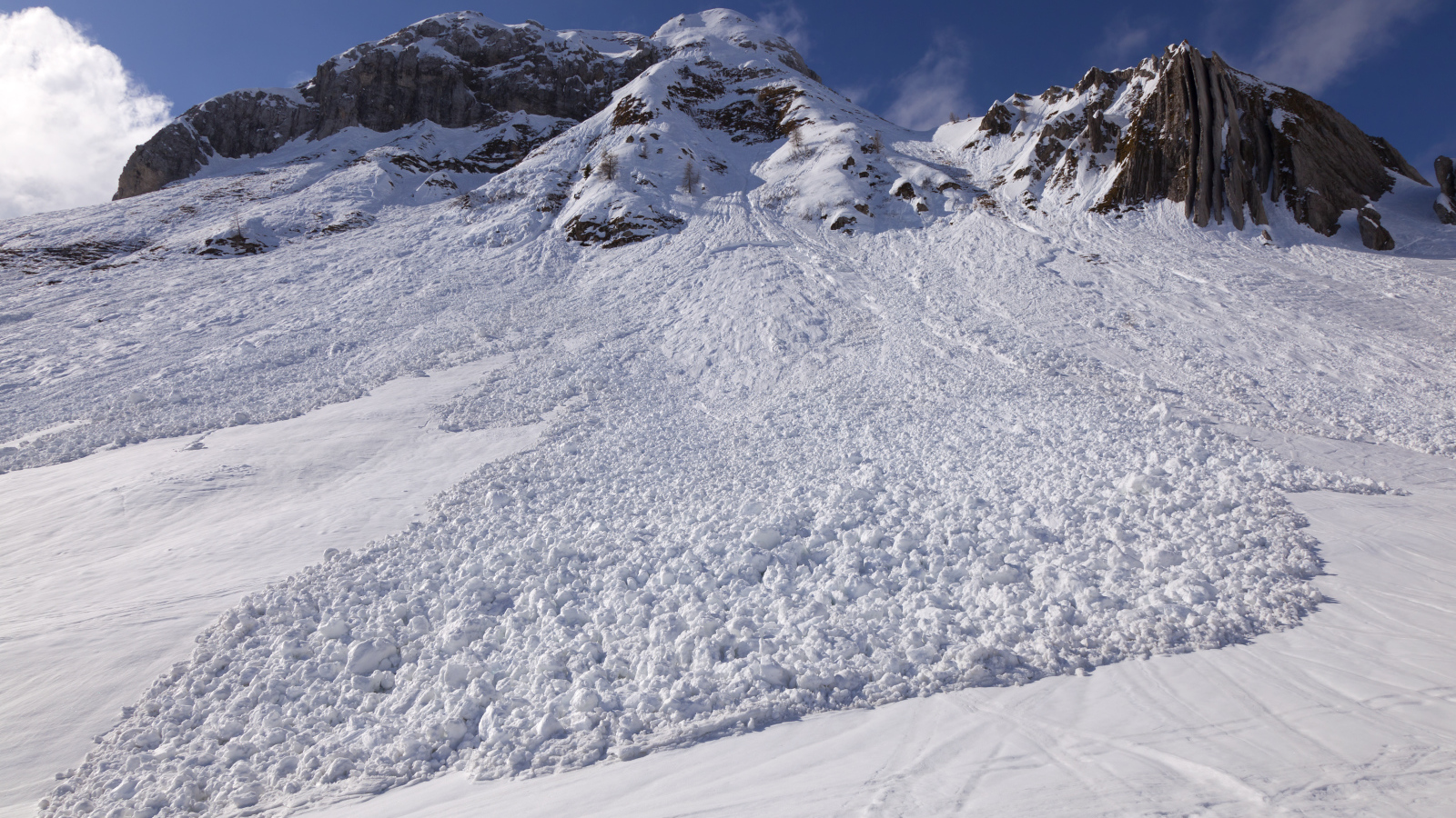 Белая лавина сходит с гор солнечным днем