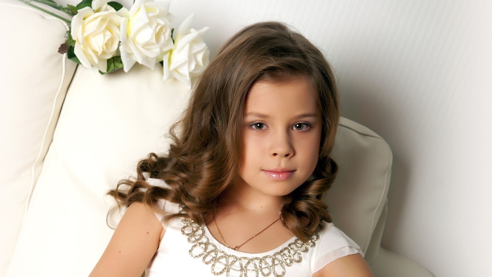 Красивая маленькая девочка сидит в кресле