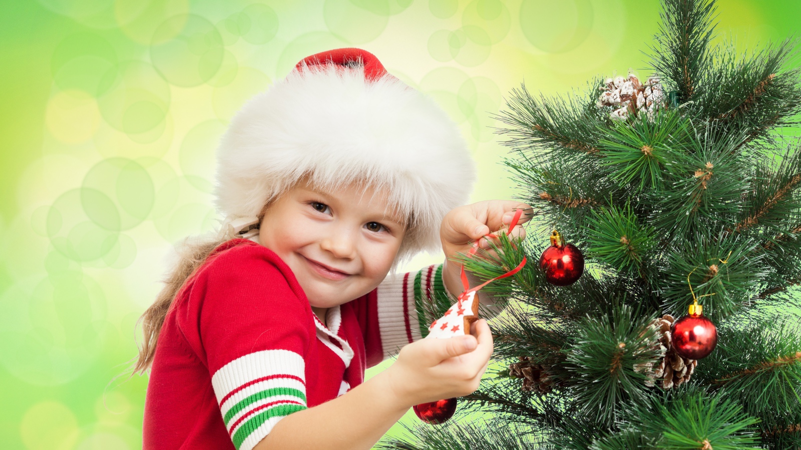 Little beautiful girl decorates a Christmas tree for the New Year.
