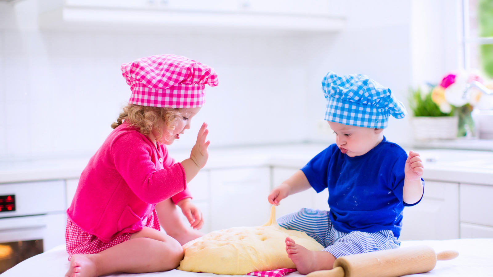 Маленькие мальчик и девочка на кухне с тестом