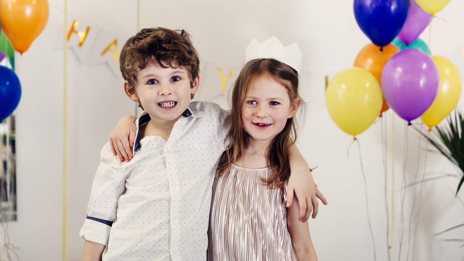 Маленькие мальчик и девочка на празднике с воздушными шарами