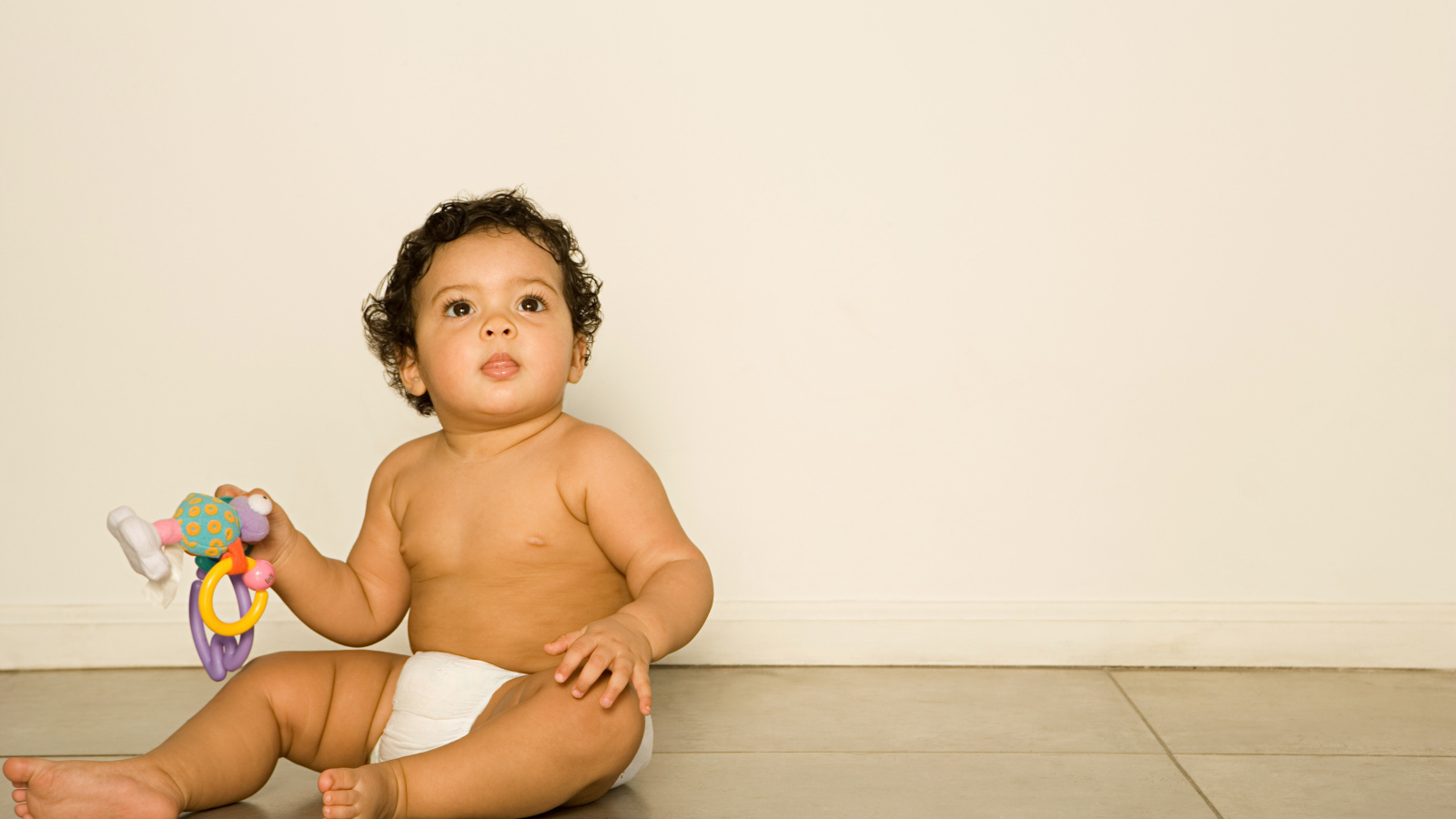 Маленький мальчик сидит на полу с игрушкой