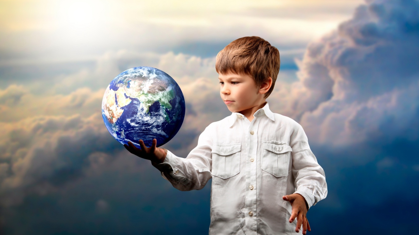 Маленький мальчик с планетой земля в руке