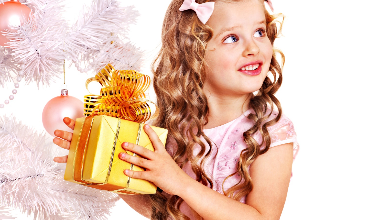 Маленькая милая девочка с подарком у елки на белом фоне 