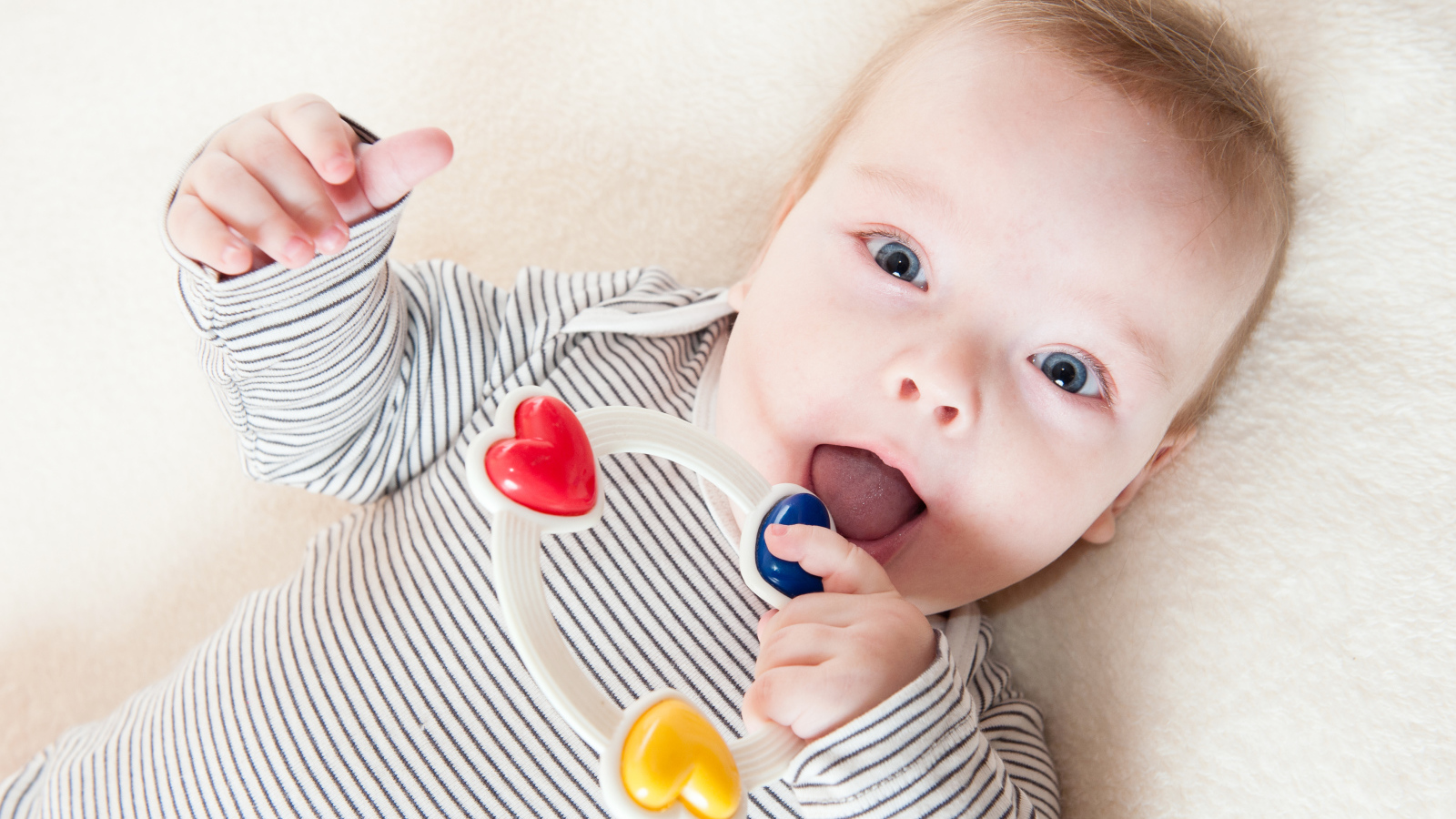 Маленький забавный голубоглазый ребенок с погремушкой