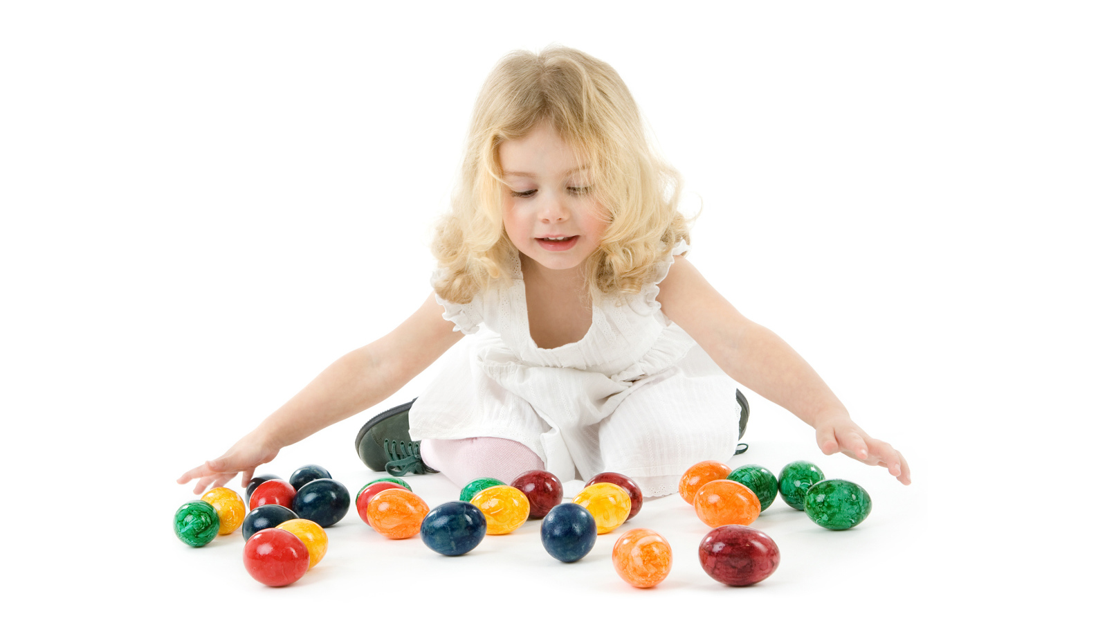 Маленькая девочка блондинка с крашеными яйцами на белом фоне