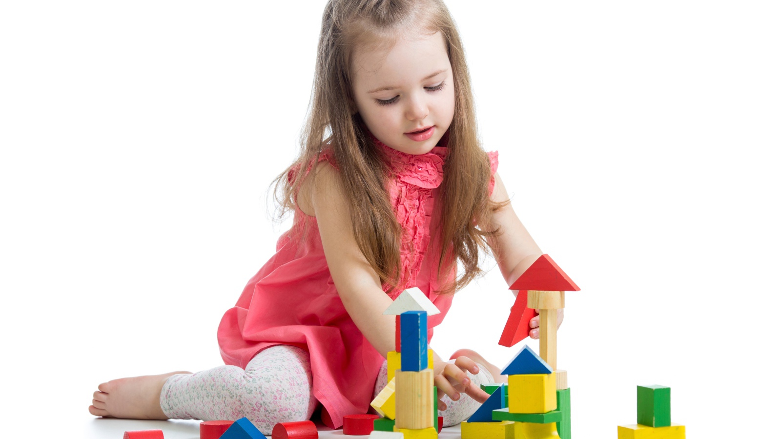 Маленькая девочка строит домик из кубиков на белом фоне