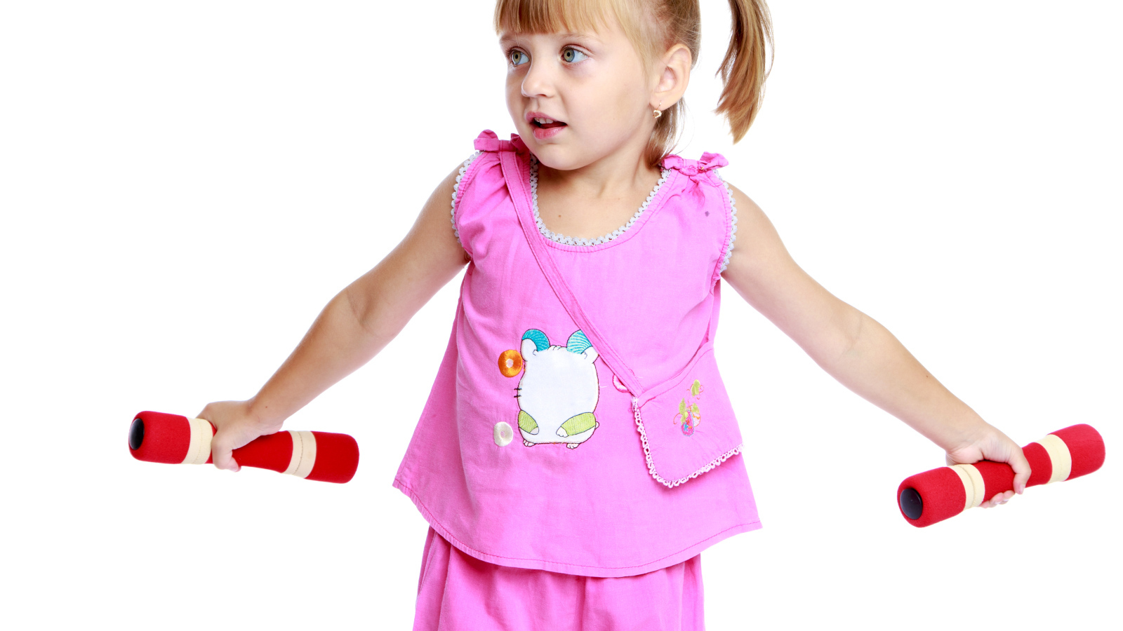 Маленькая девочка в розовом костюме с гантелями в руках на белом фоне