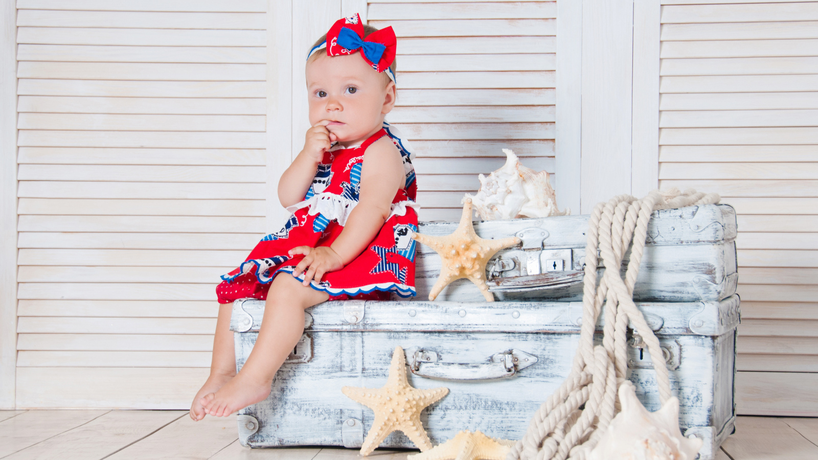 Маленькая девочка сидит на чемодане с морскими звездами