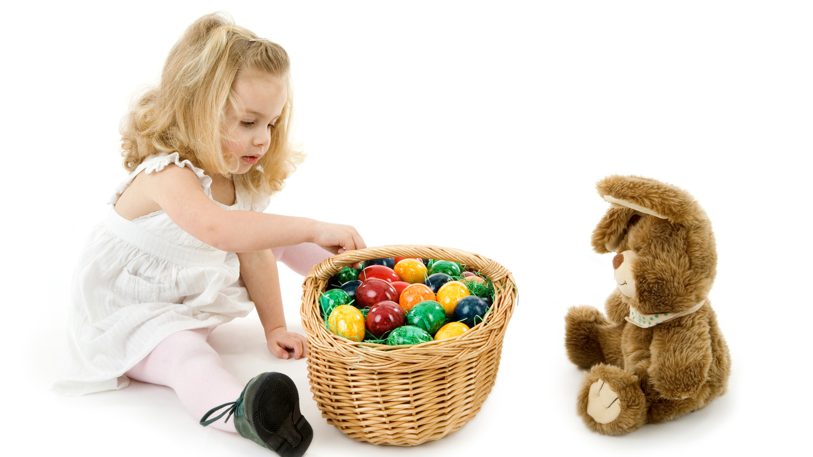Маленькая девочка с корзиной крашеных яиц и игрушечным кроликом