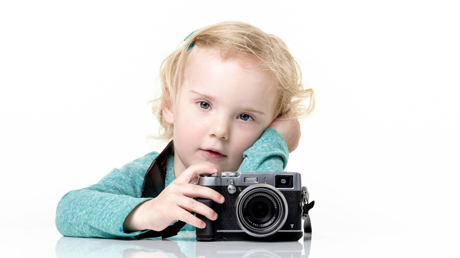 Маленькая девочка с фотоаппаратом на белом фоне