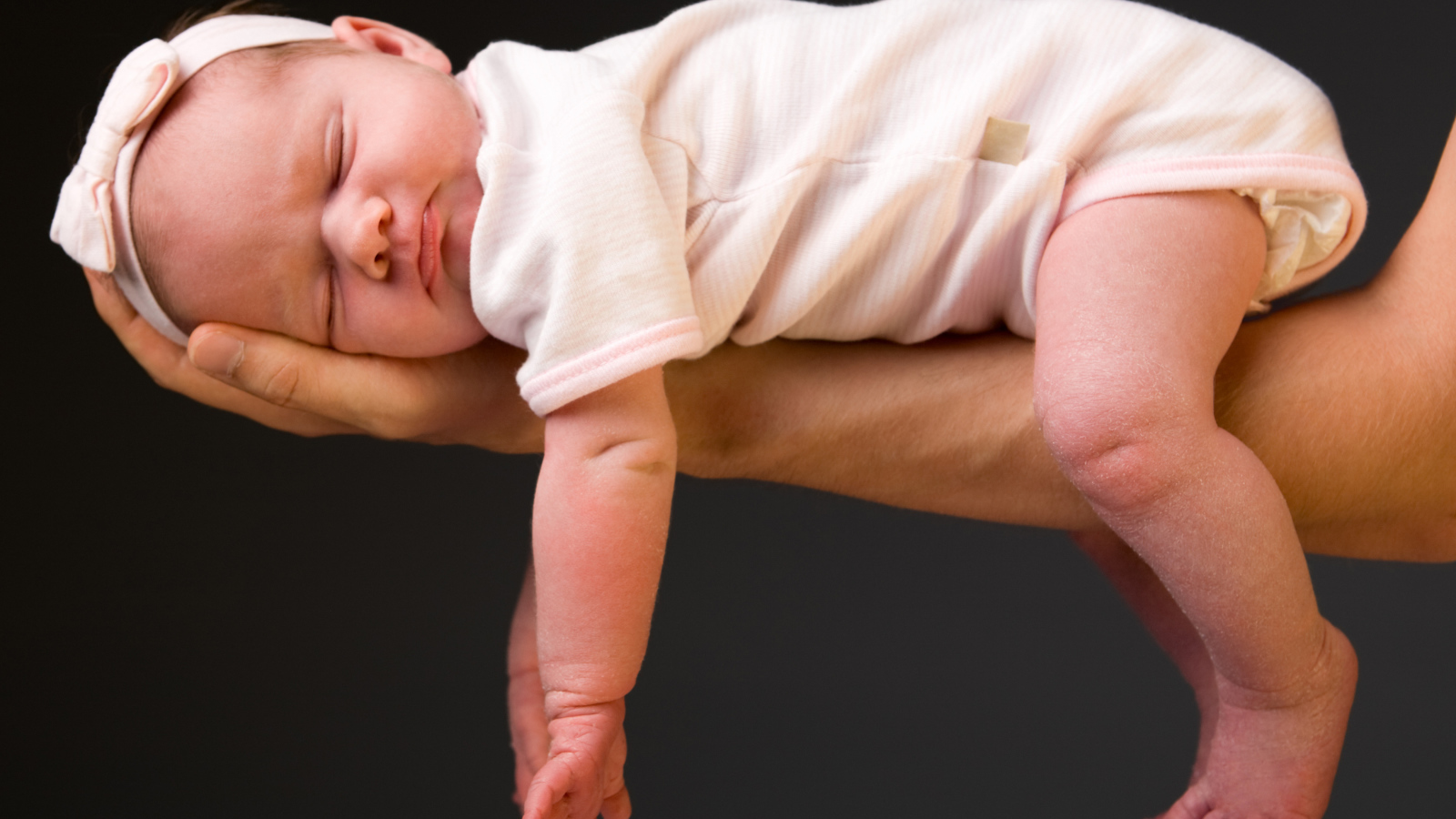 Спящий ребенок на руке у папы на сером фоне