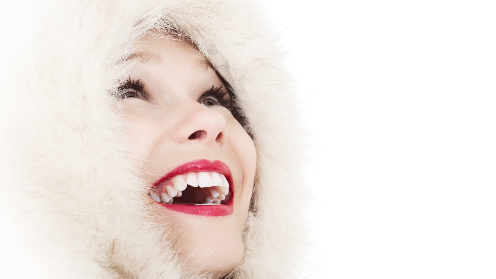 Улыбающаяся девушка в меховом капюшоне на белом фоне