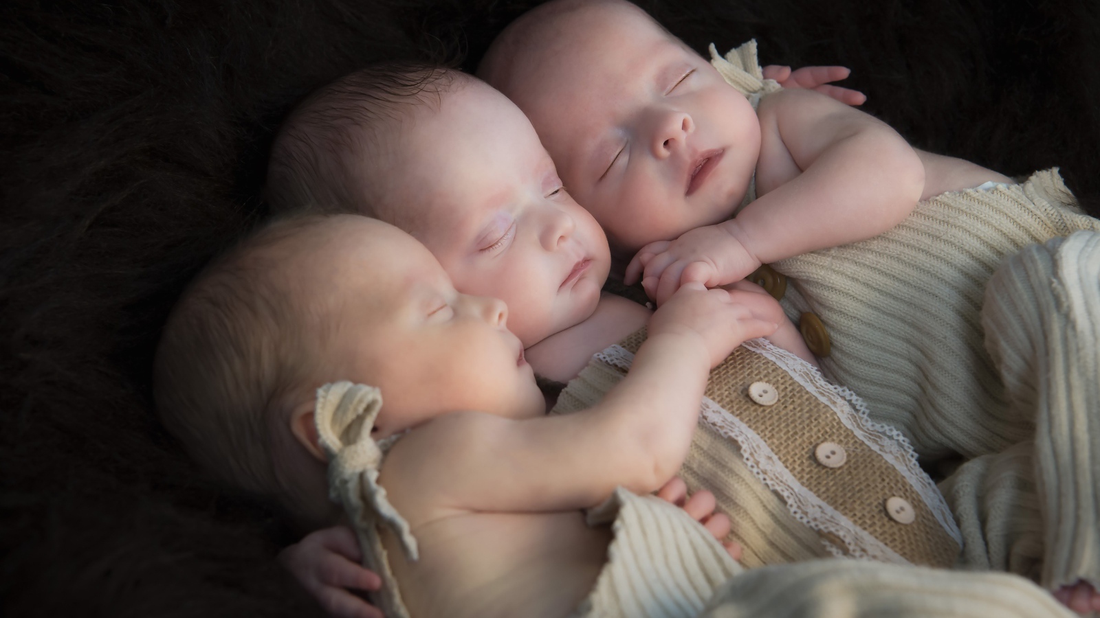 Три маленьких грудных ребенка спят обнявшись 