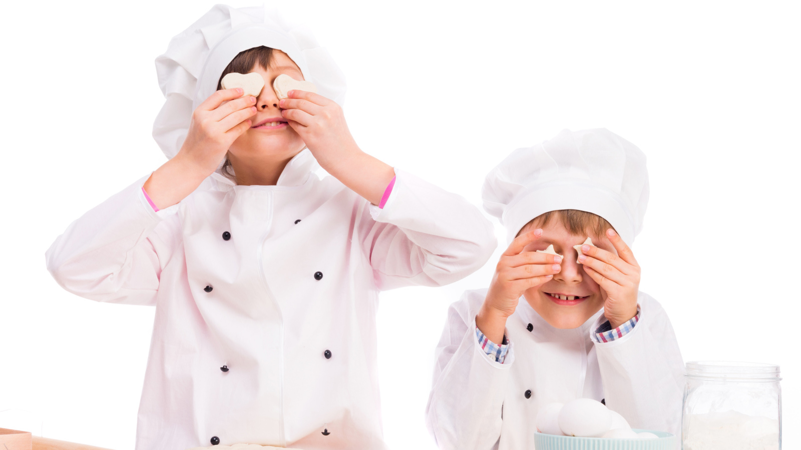 Два маленьких мальчика в костюмах повара на кухне делают печенье