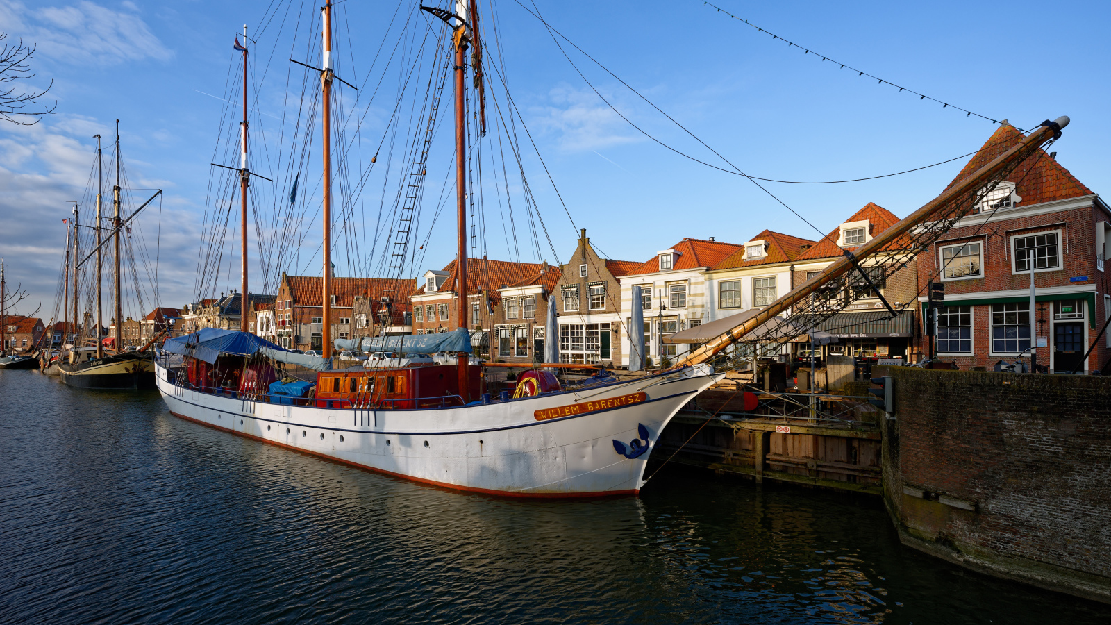Парусное судно Willem Barentsz с опущенными парусами на причале у домов
