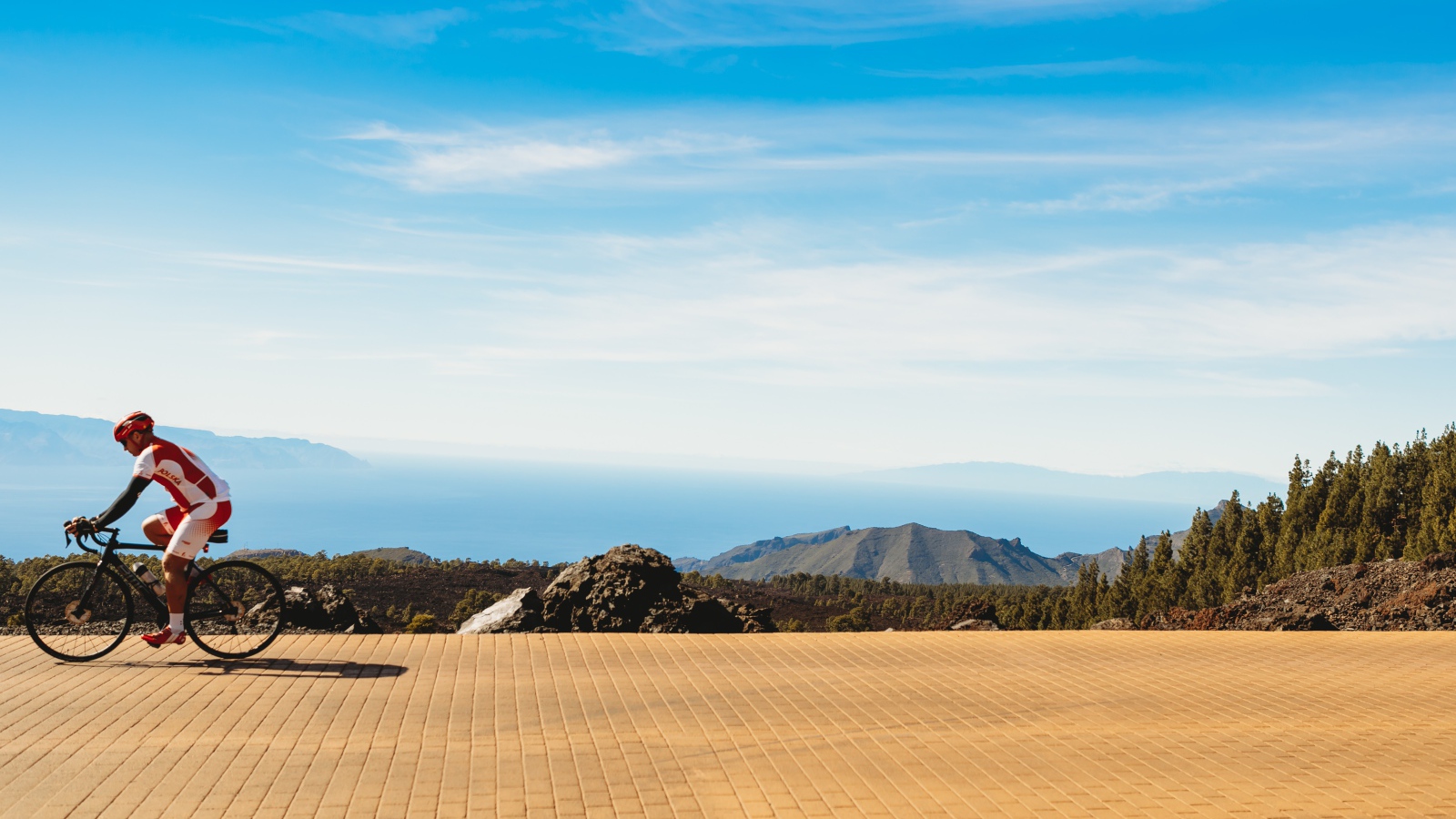 Велосипедист едет по дороге на фоне голубого неба