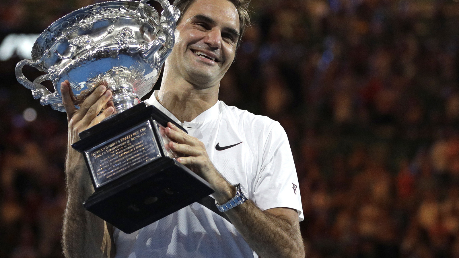 Улыбающийся швейцарский теннисист Роджер Федерер с наградой в руках