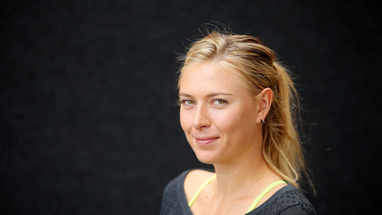 Улыбающаяся блондинка, теннисистка Мария Шарапова на сером фоне