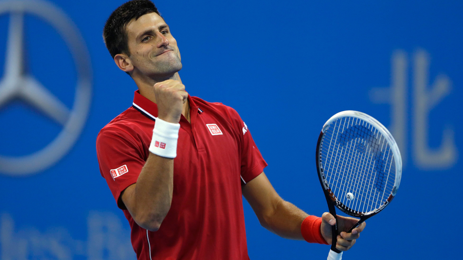 Теннисист Новак Джокович с ракеткой радуется на корте