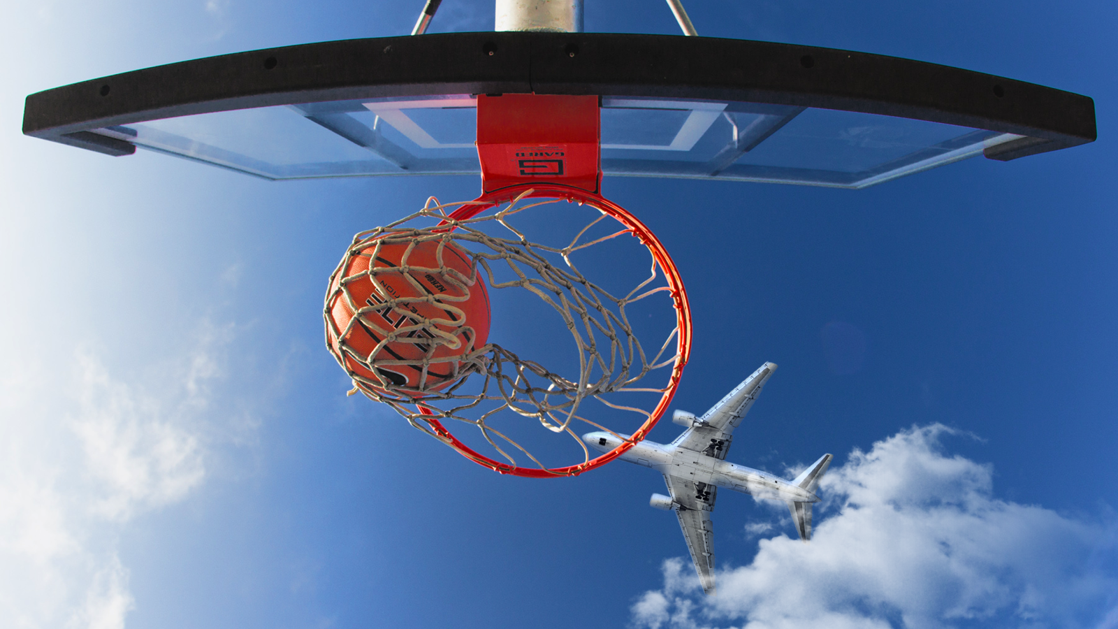 Самолет пролетает над баскетбольным кольцом в голубом небе 