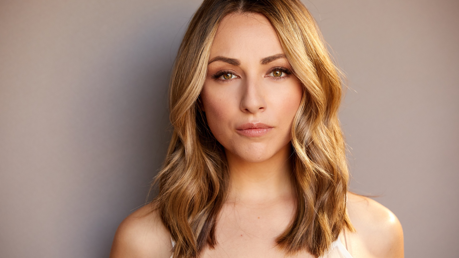 Красивая блондинка Никки Поснер на сером фоне 