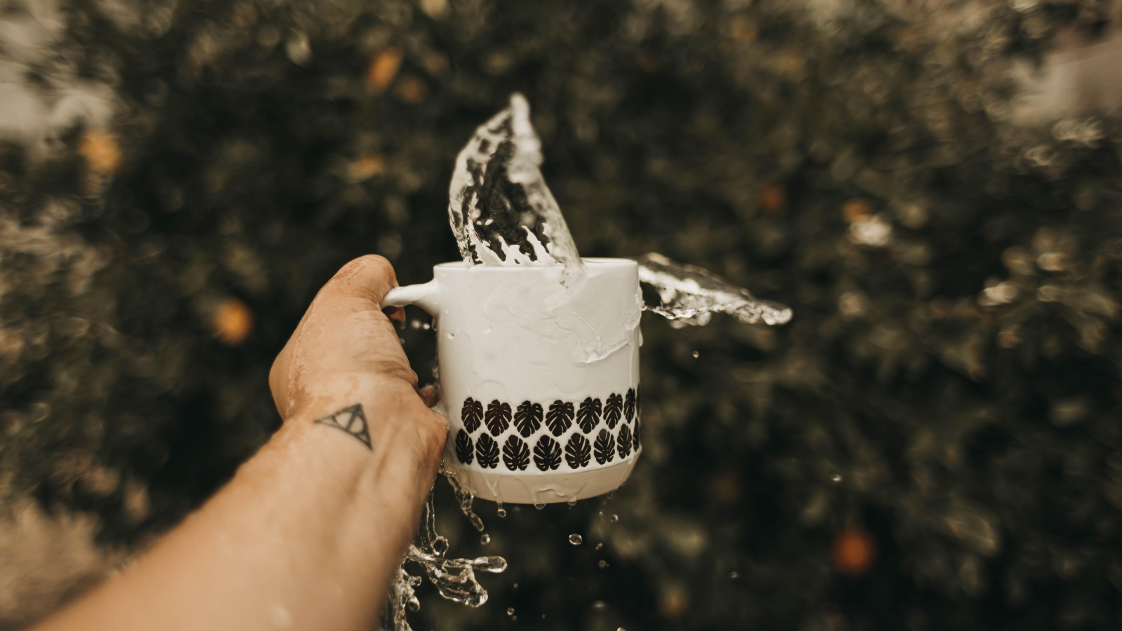 Чашка с водой в руке с татуировкой 