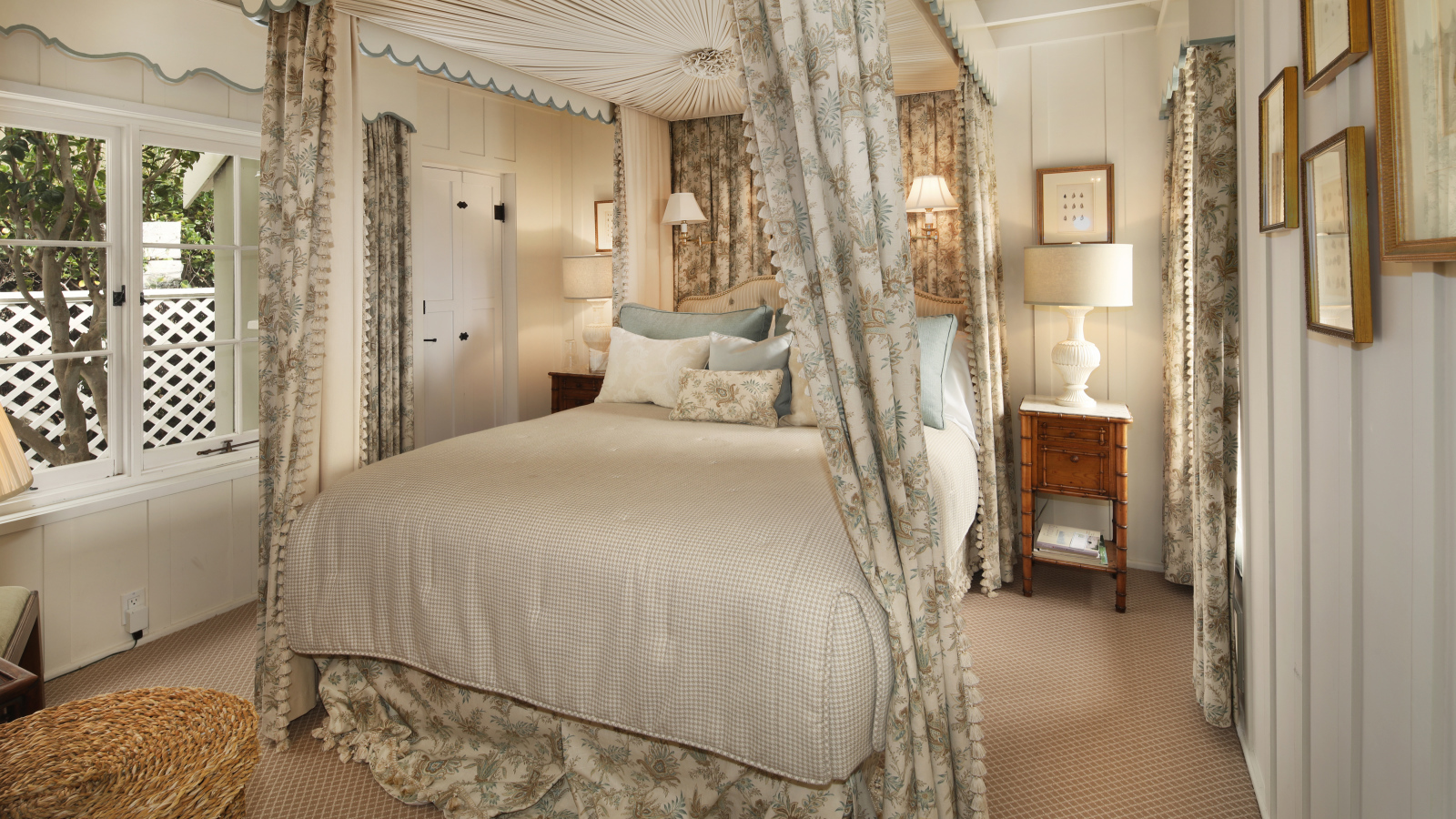 Высокая кровать с занавесками в спальной комнате в пастельных тонах 