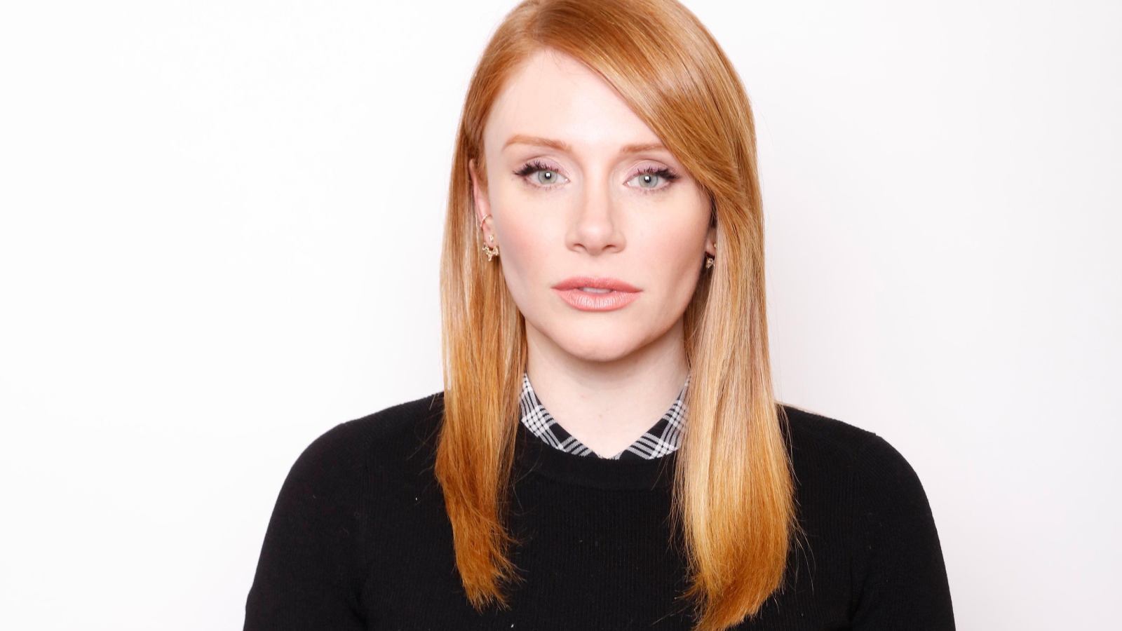 Рыжеволосая актриса Брайс Даллас Ховард в черном свитере на белом фоне