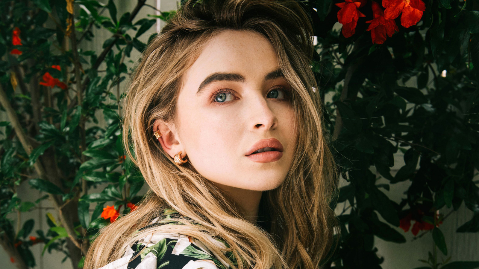 Молодая красивая актриса Сабрина Карпентер у красных цветов