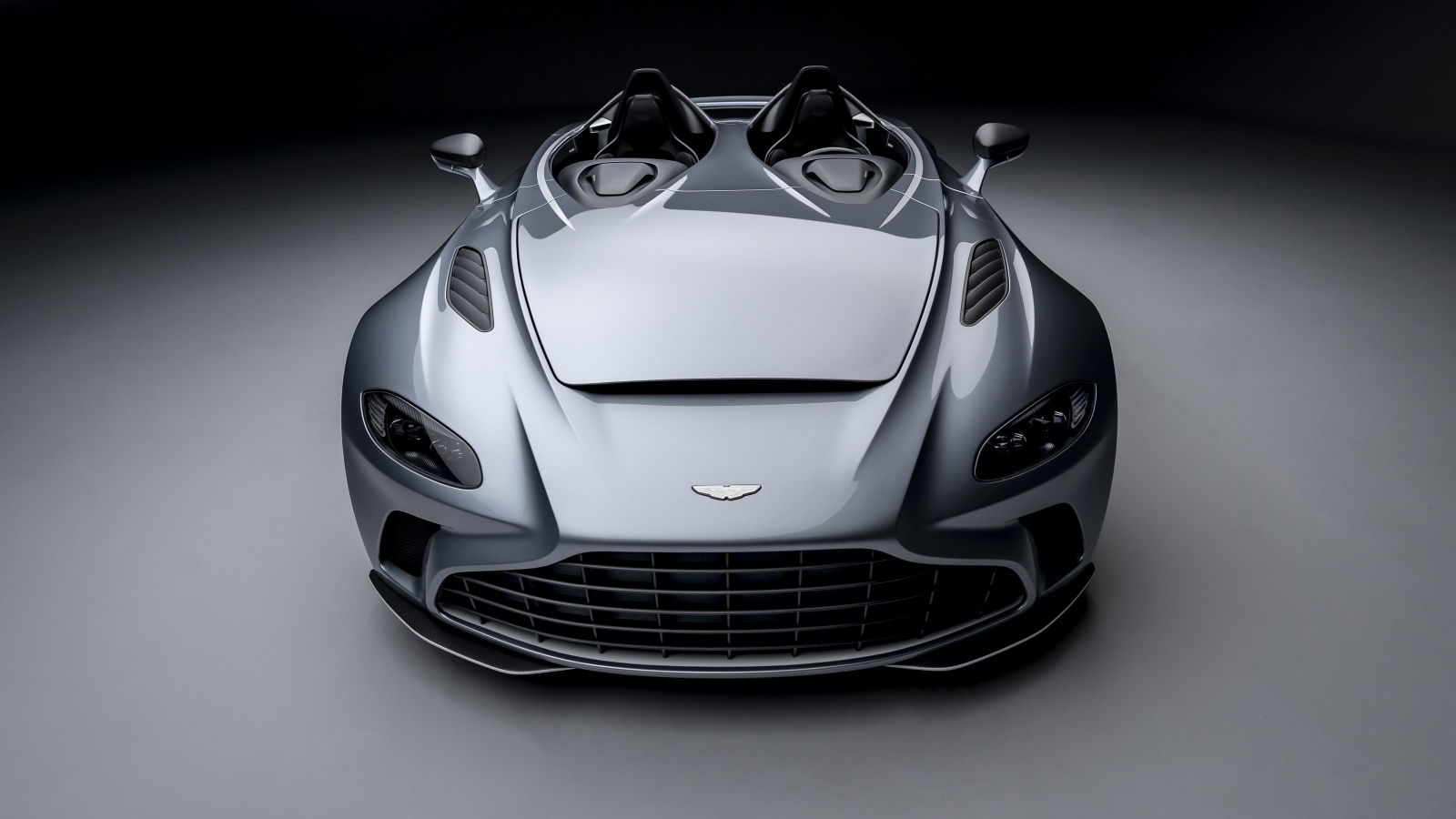 Серебристый автомобиль Aston Martin V12 Speedster 2020 года на сером фоне