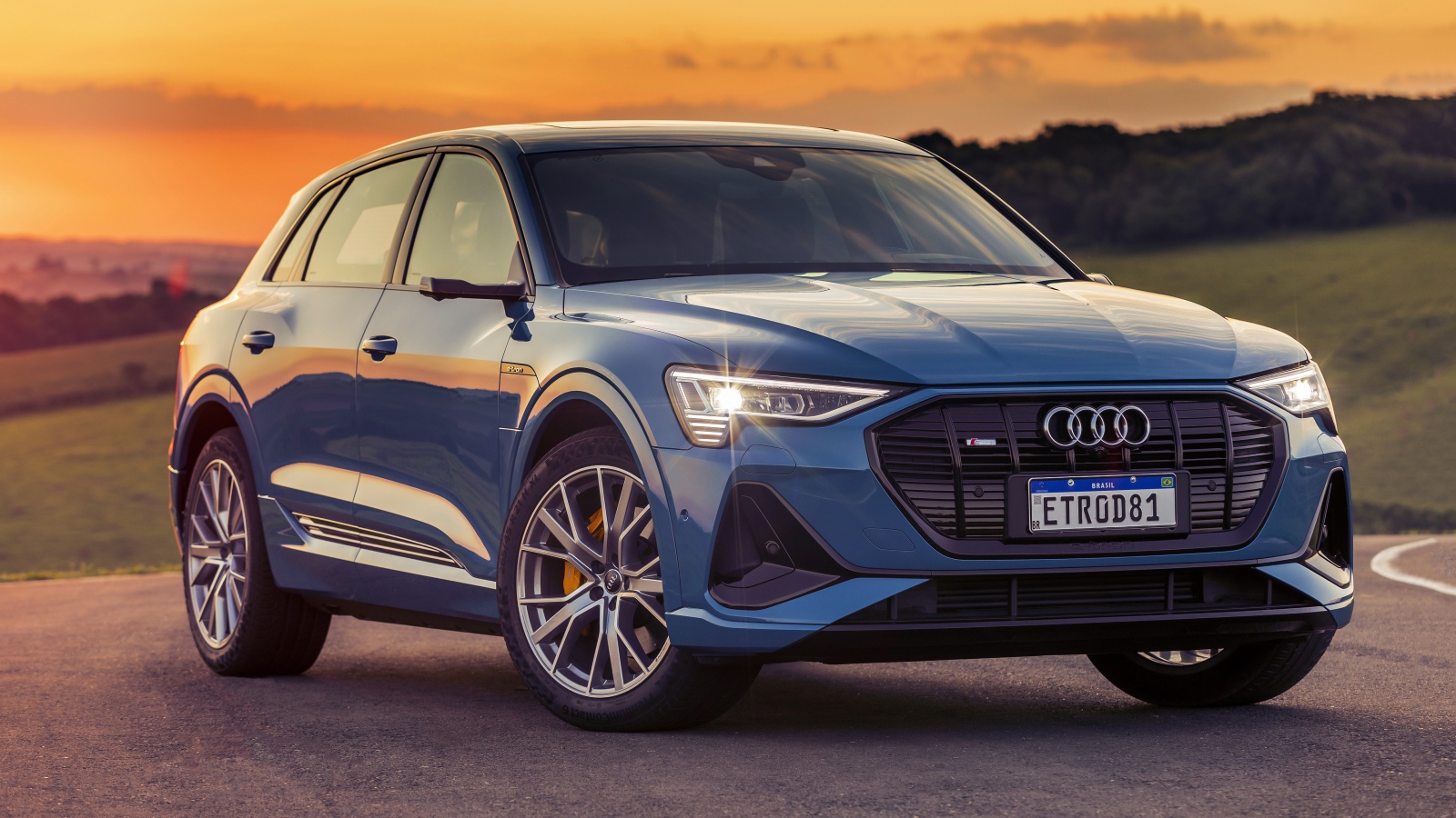 Синий автомобиль Audi E-Tron 55 Quattro S Line 2020 года на закате