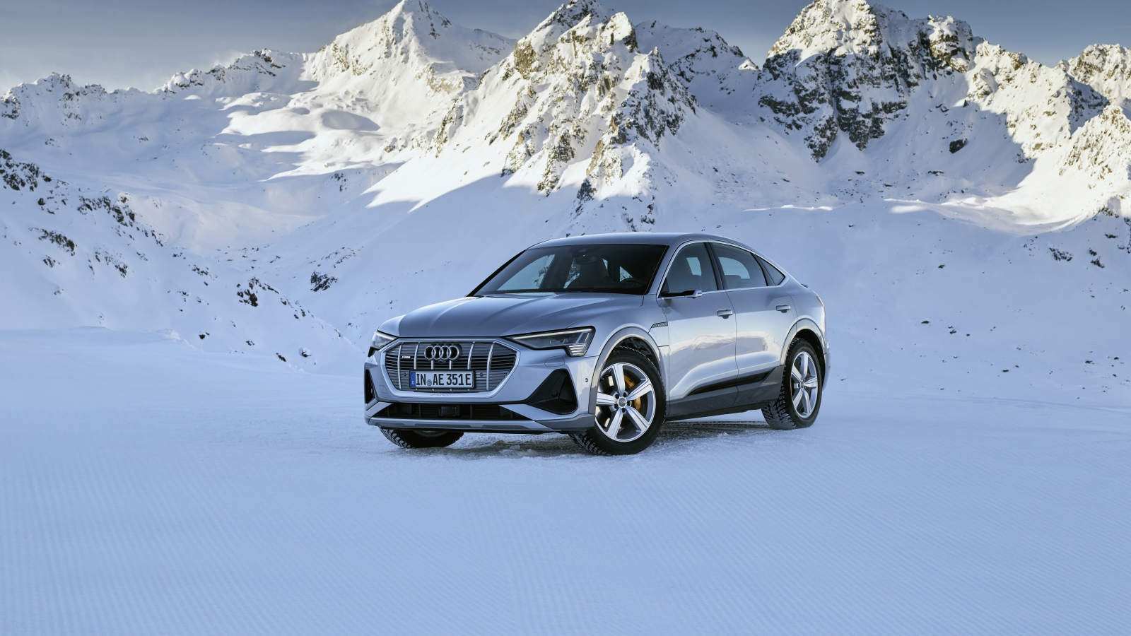 Автомобиль Audi E-Tron 55 Quattro Sportback S Line, 2020 года на фоне заснеженных гор 