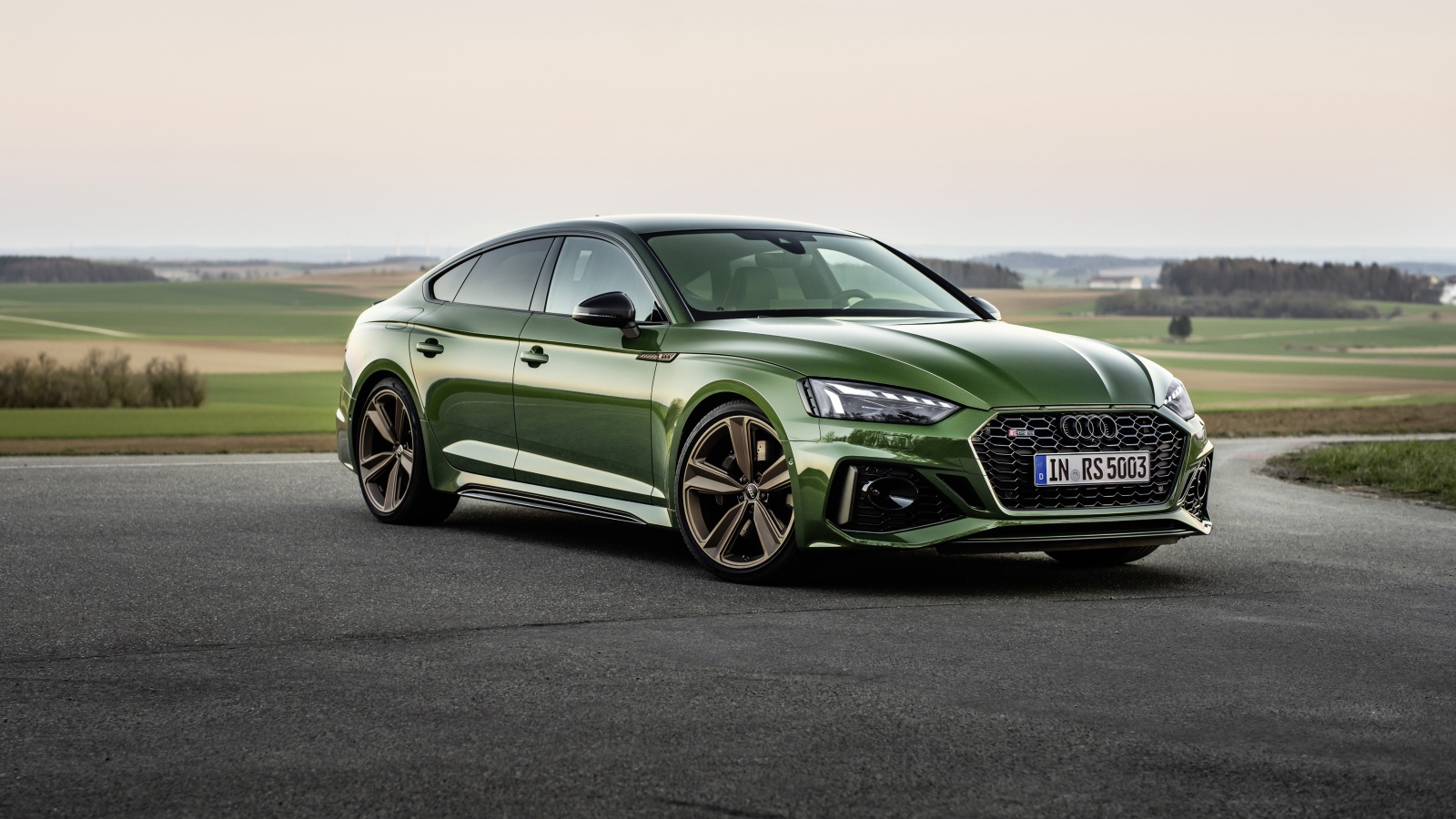 Зеленый автомобиль Audi RS 5 Sportback 2020 года на фоне поля