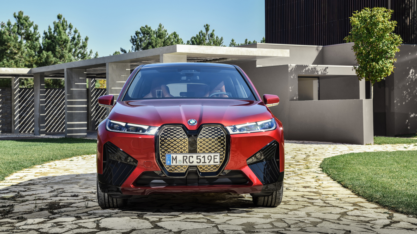 Красный автомобиль BMW IX 2021 года у дома