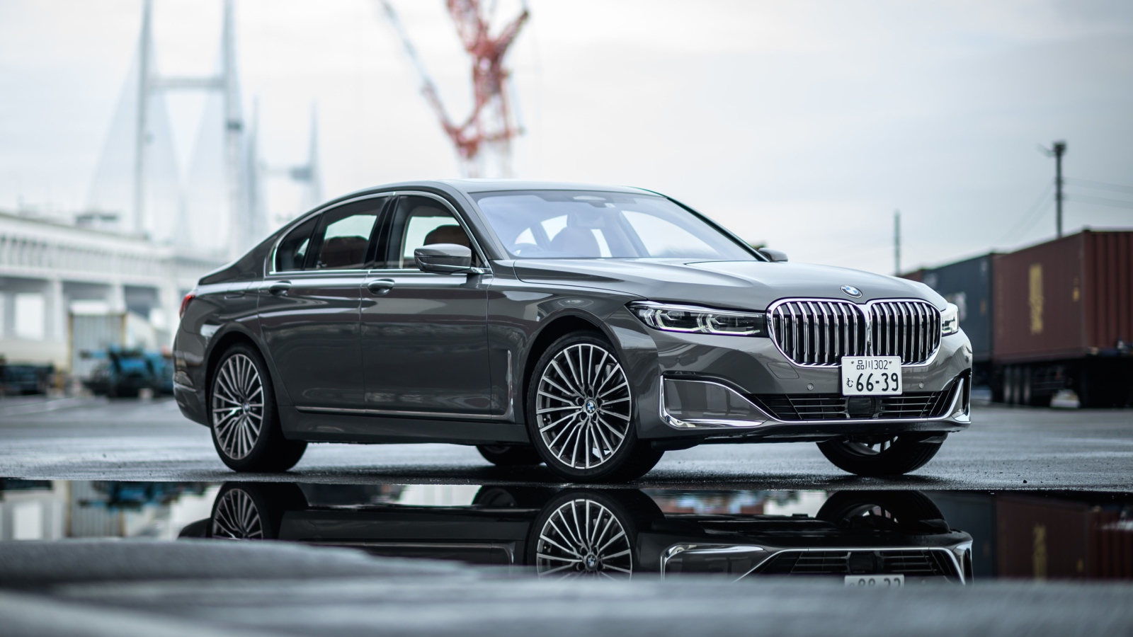 Серебристый автомобиль BMW 745e на мокром асфальте 