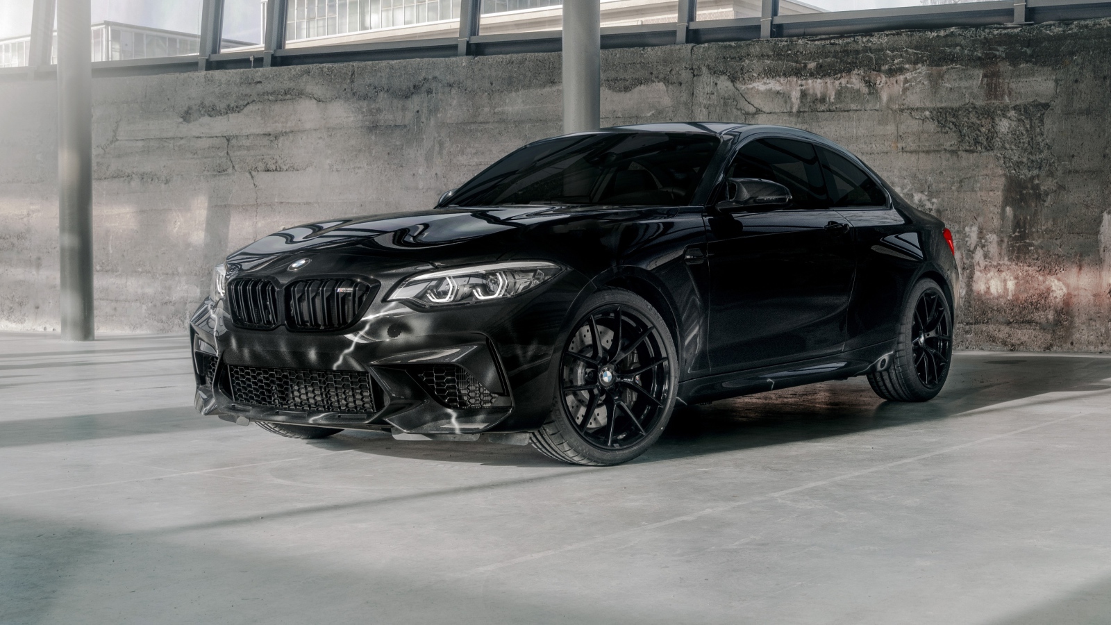 Черный автомобиль  BMW M2, 2020 года у бетонной стены