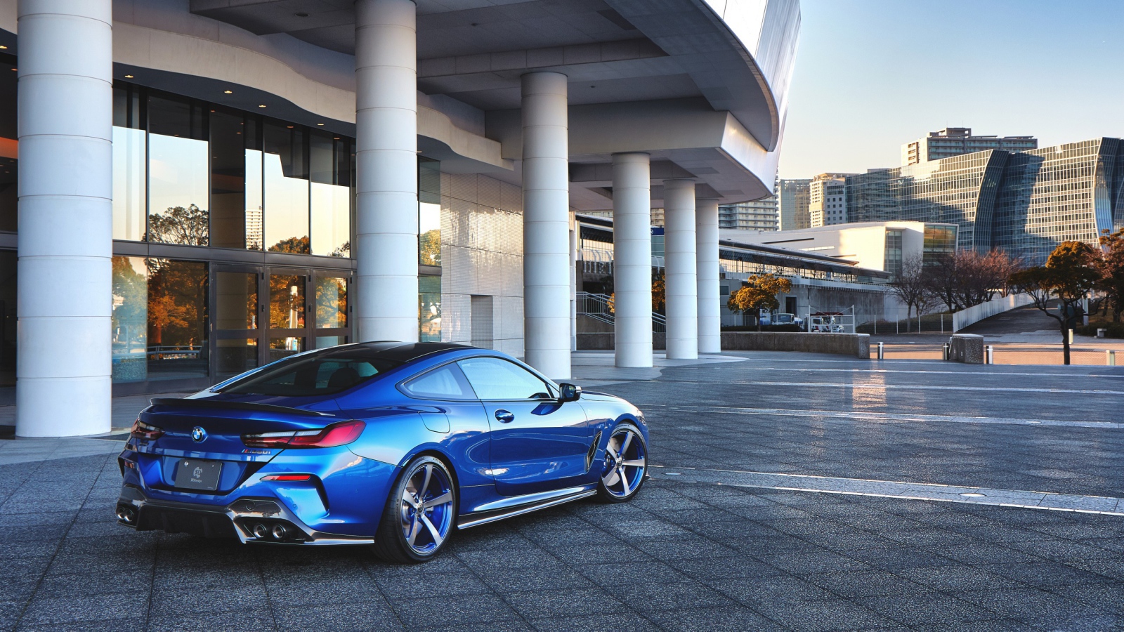 Синий автомобиль BMW M850i XDrive Coupe 2020 года у здания вид сзади