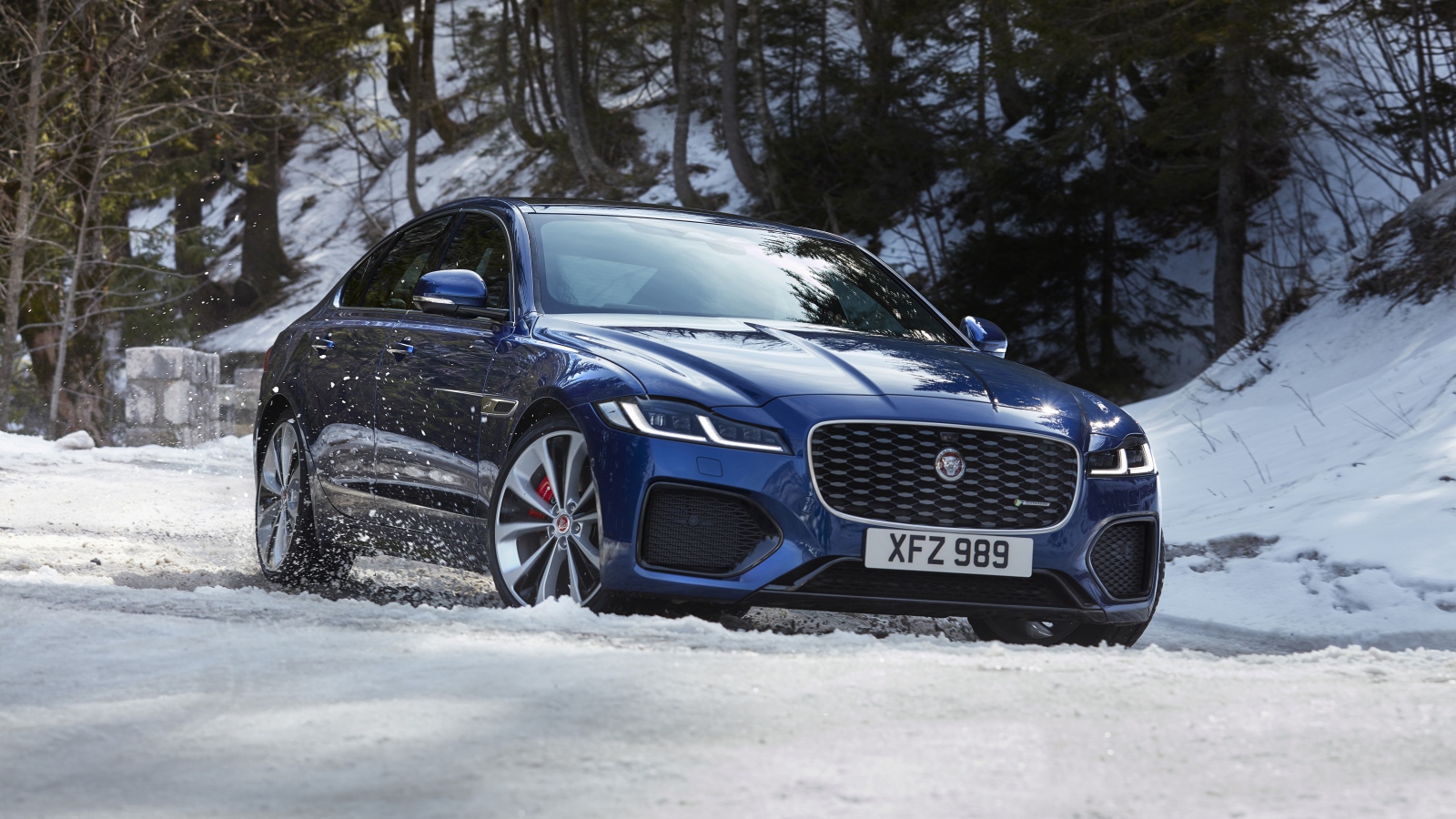 Синий Jaguar XF P300 AWD R-Dynamic 2020 года в заснеженном лесу 