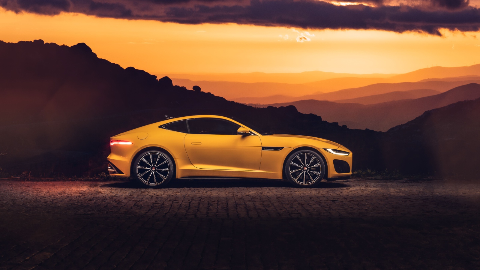 Желтый автомобиль jaguar f type 2020 года на закате 